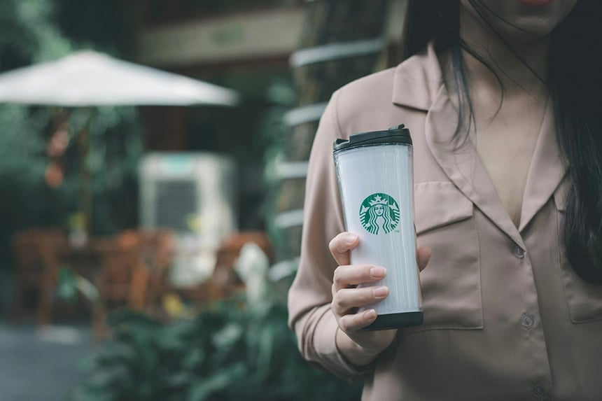 Kvinna håller i en Kaffemugg som har Starbucks logotyp 