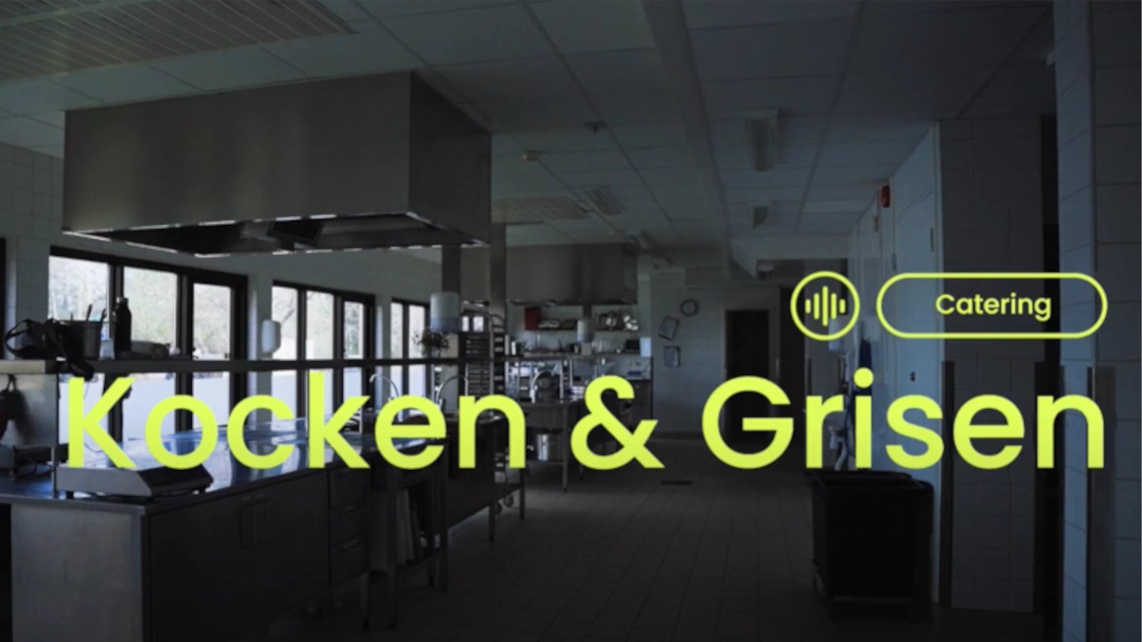 Neongul text "Kocken & Grisen-Catering" mot en bakgrund i ett nedsläckt kök.