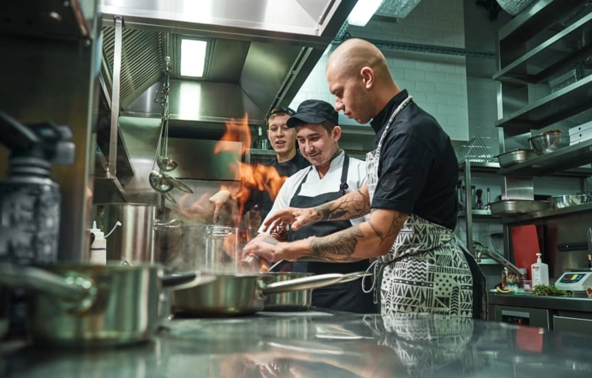 Tre fra kjøkkenpersonalet står og lager mat på restauranten.