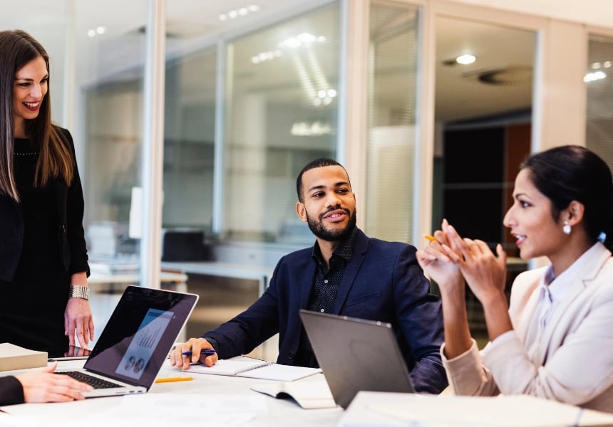 Kontoransatte sitter med bærbare PC-er og har møte.