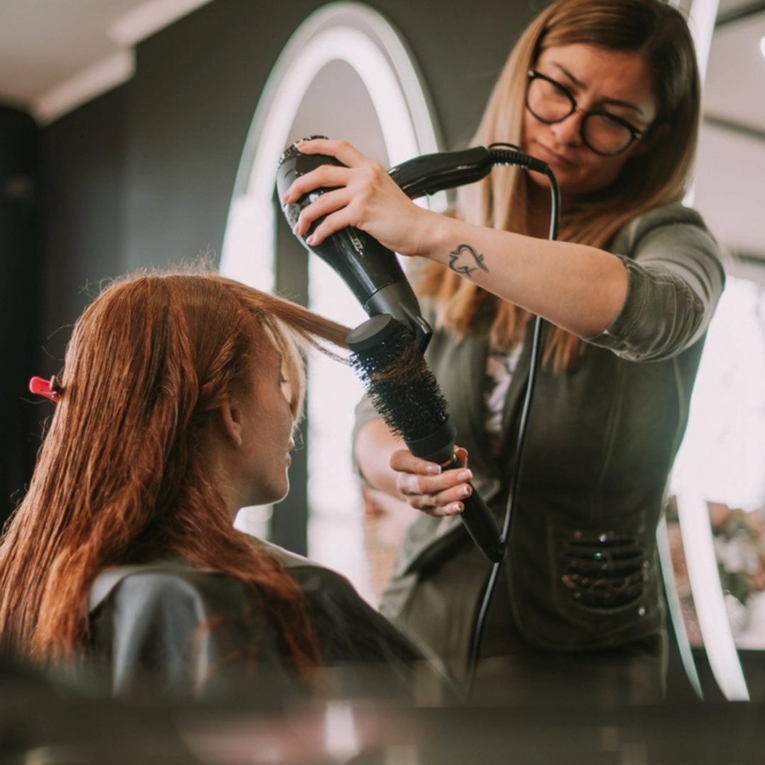 Frisør føner håret til kunden.