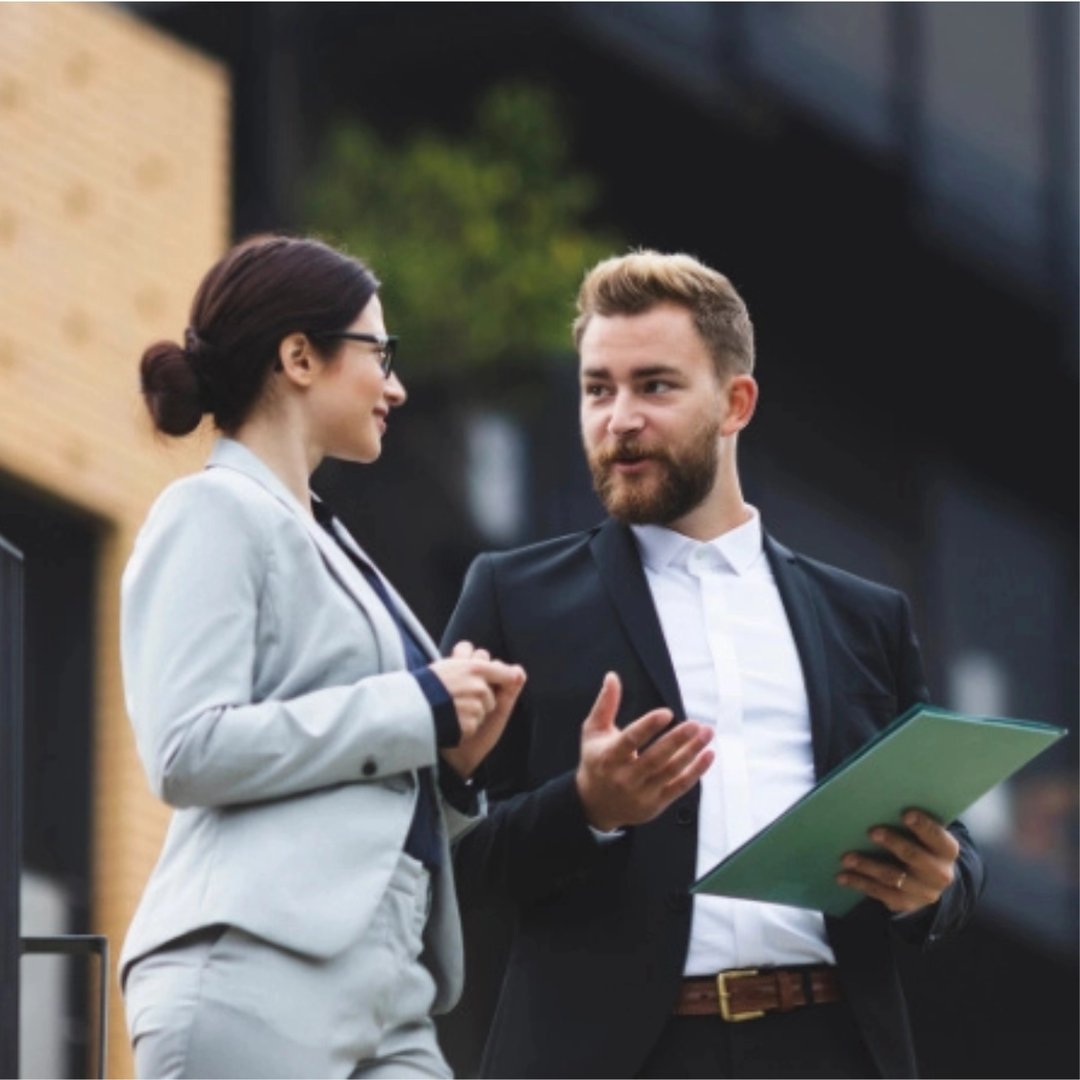 Meglere står og diskuterer foran en stor eiendom.