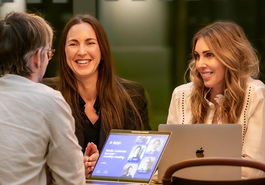 Skrattande kollegor i matchande lila tröjor.