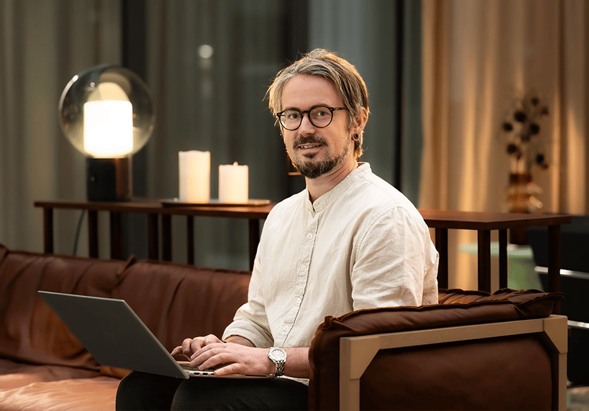 Medarbejder hos Robin sidder med en laptop og kigger mod kameraet.